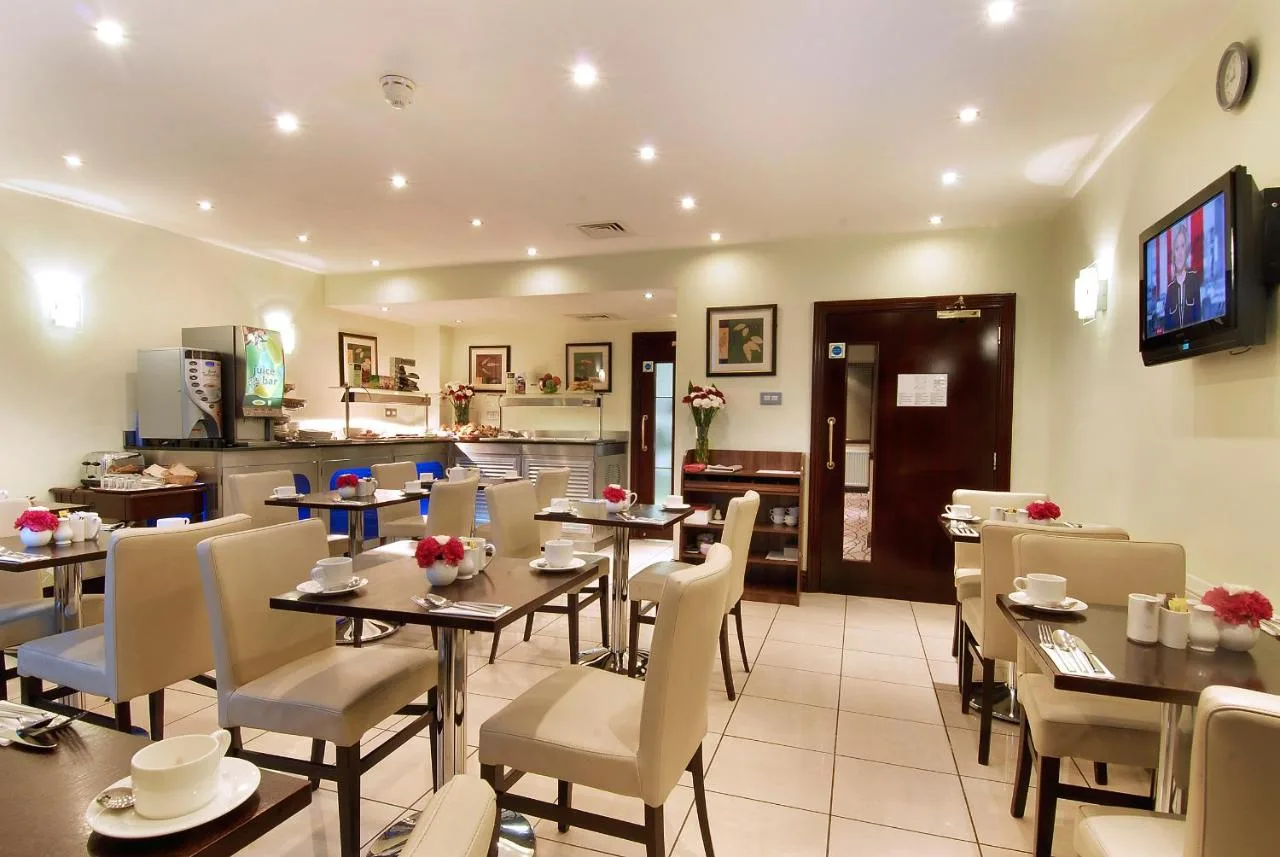 a restaurant with tables and chairs and a kitchen at The Premier Notting Hill in London